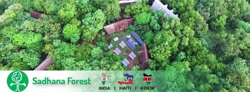 Picture of sadhana forest an aerial view of forest with solar panels in between along with huts.